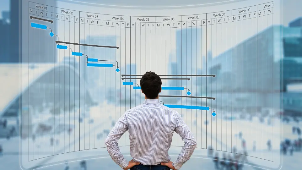 Project manager reviewing tasks using a Gantt chart on a computer screen.